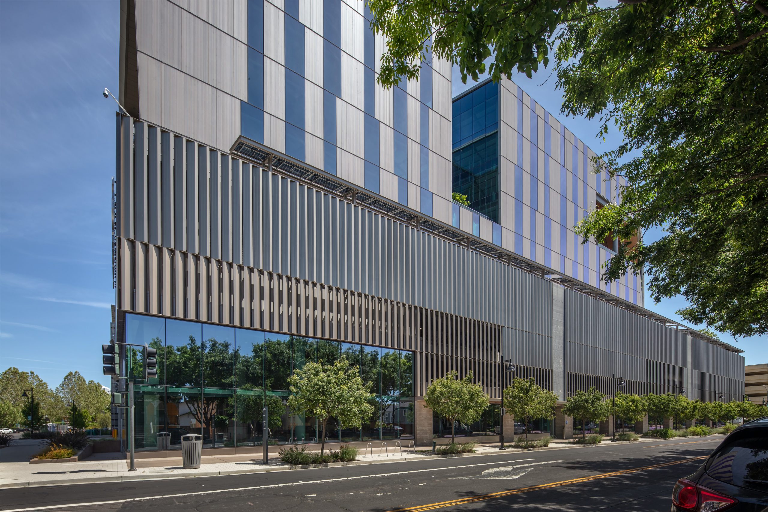 Street level view of the corner and side view of building, lined with trees.